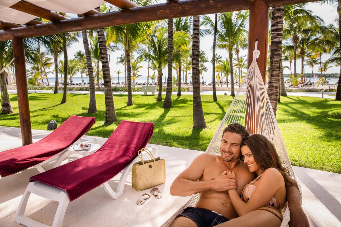 A couple relaxes in a hammock on a palm-shaded terrace at Barceló Maya Caribe.