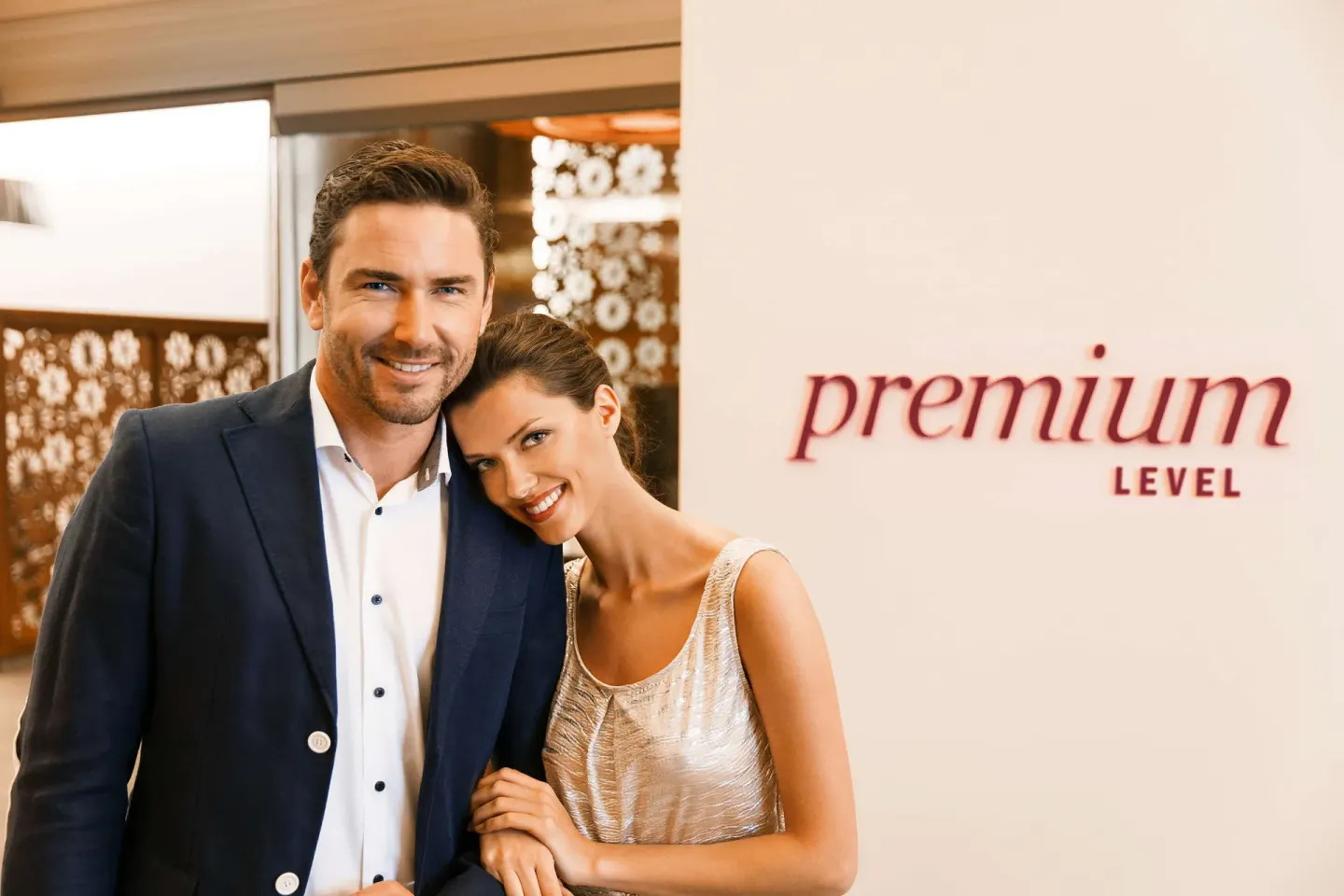 Couple posing beside a Premium Level wall sign at Barceló Maya Caribe.