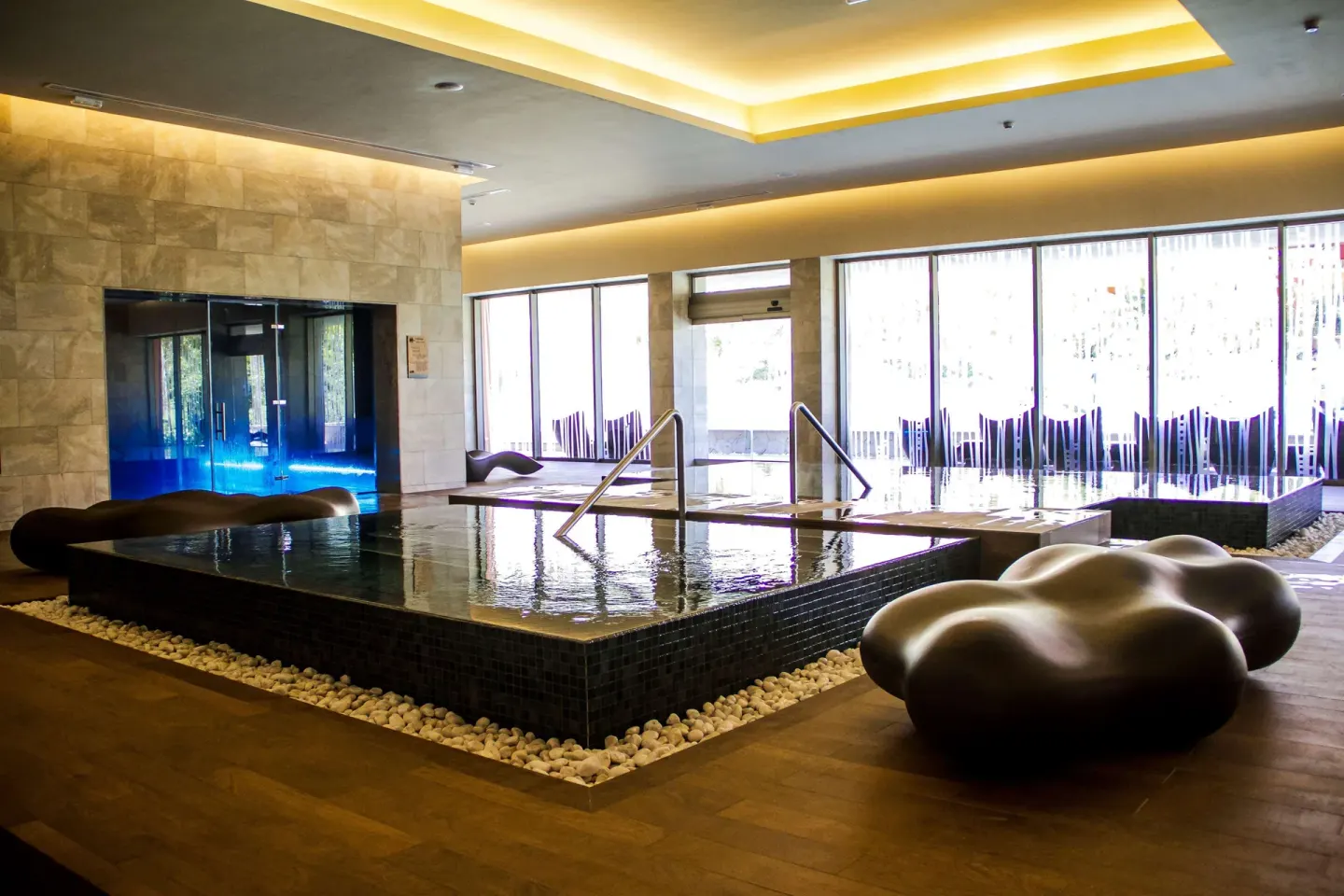 Indoor spa pool with lounge seating and large windows at Barceló Maya Caribe.