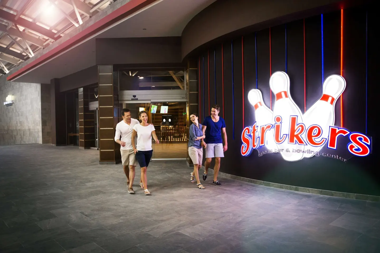 Guests walk past the Strikers bar and bowling center entrance at Barceló Maya Caribe.