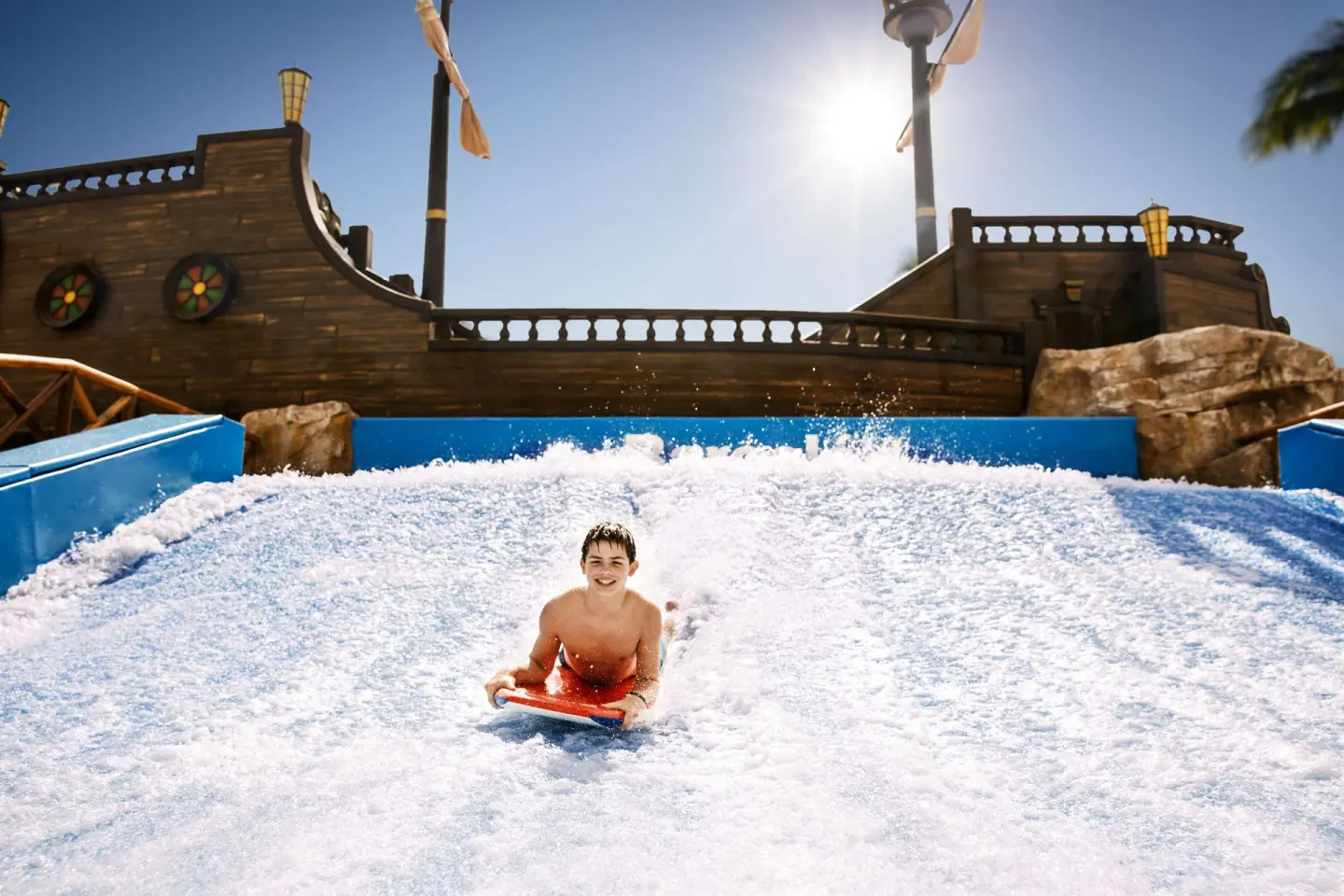 Child bodyboarding down a surf-style water attraction at Barceló Maya Caribe.