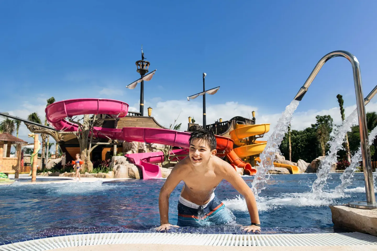 A boy climbs from the pool with water slides behind him at Barceló Maya Caribe.