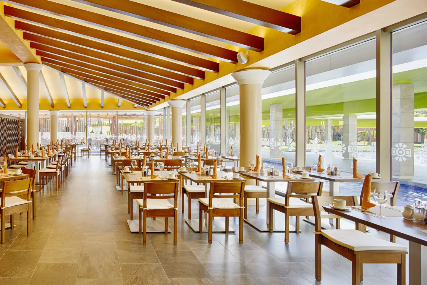 Bright dining room with set tables and large windows at Barceló Maya Caribe.
