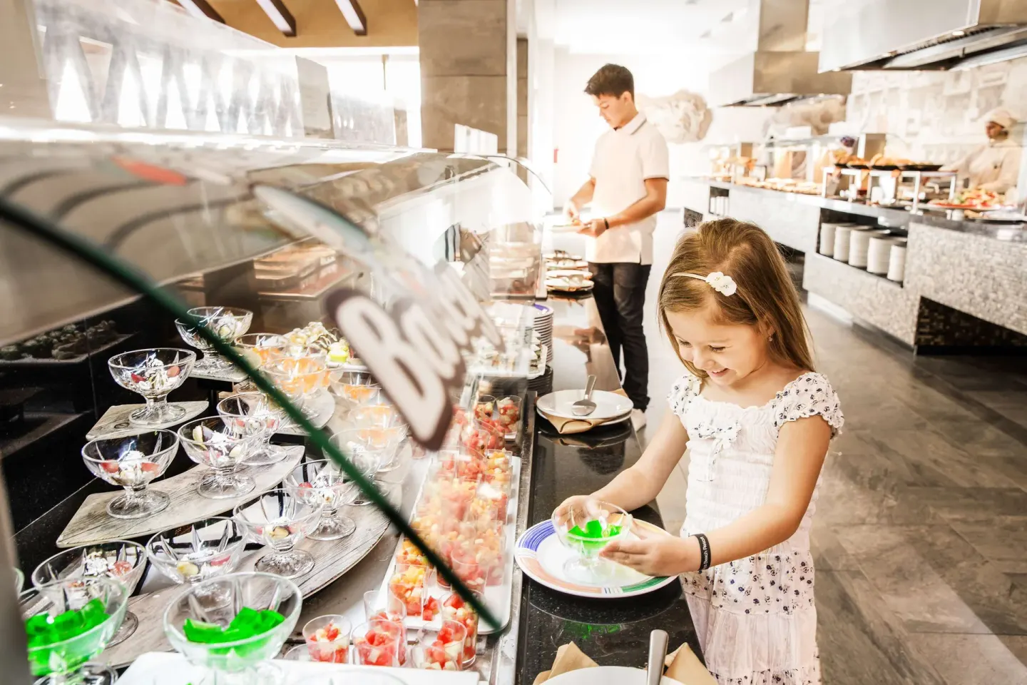 Girl choosing desserts from a buffet display at Barceló Maya Caribe.