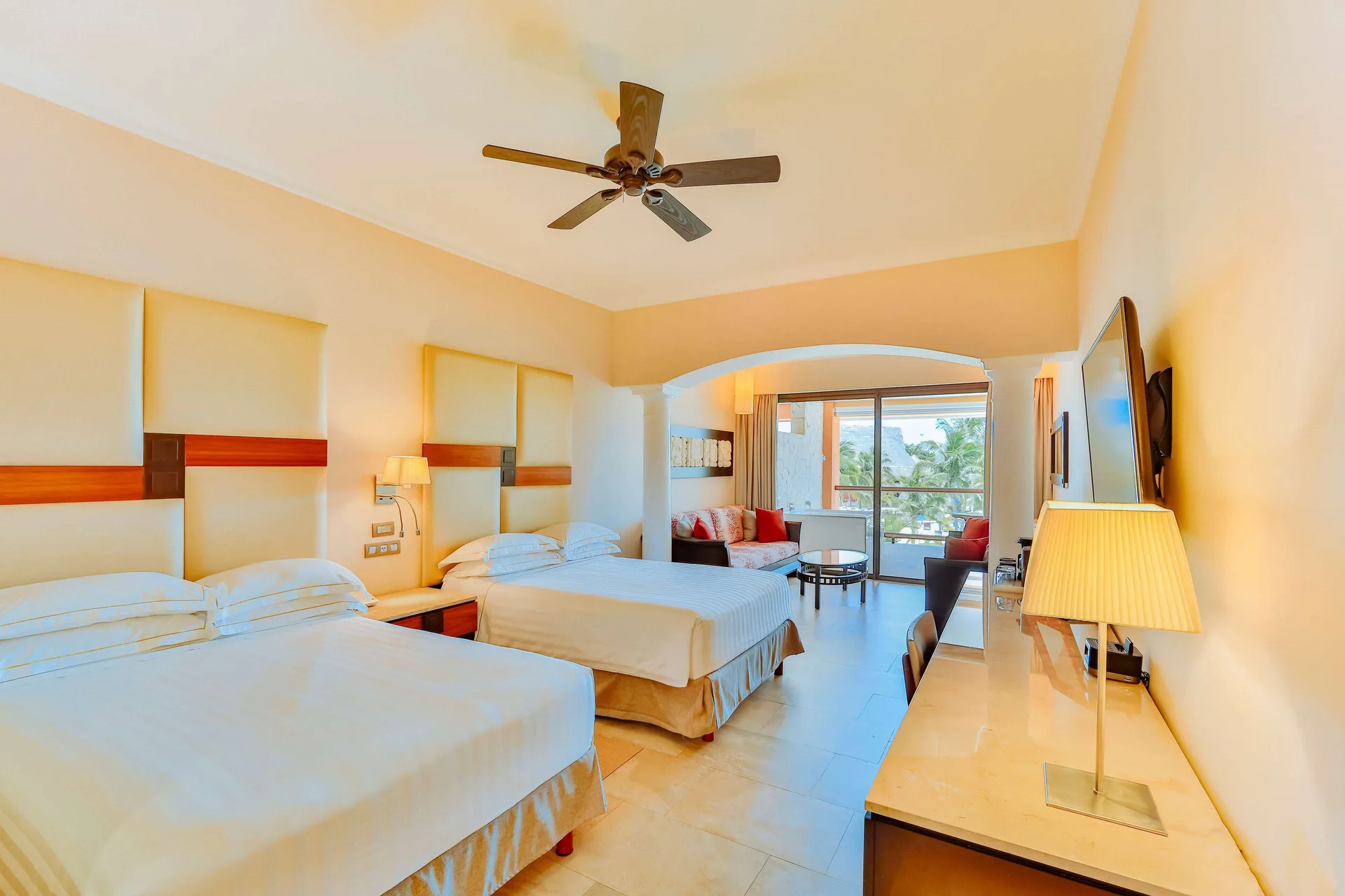 Junior Suite with two beds, desk, and balcony doors at Barceló Maya Caribe.
