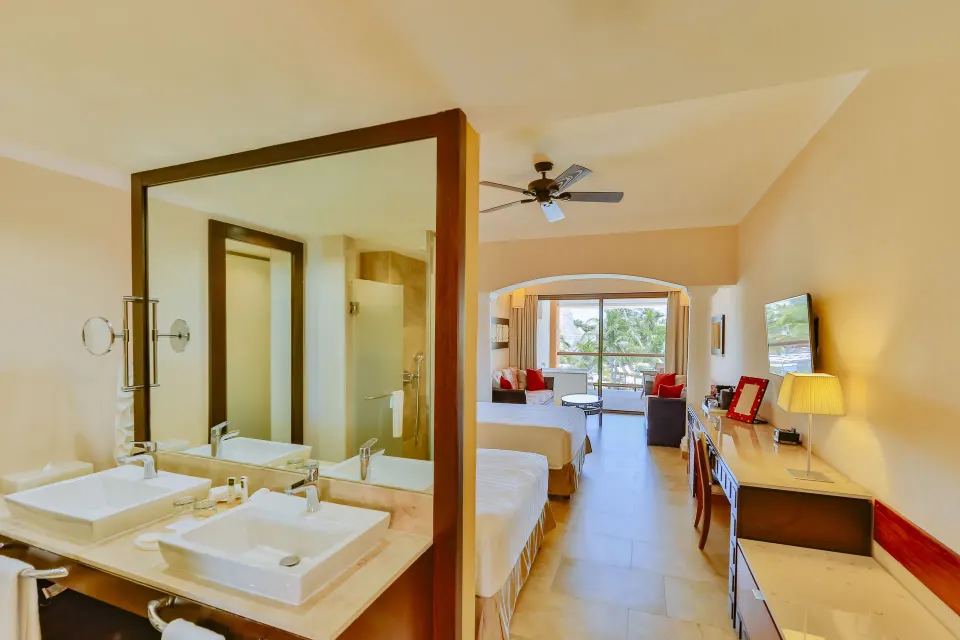 Junior Suite bathroom and bedroom with two beds at Barceló Maya Caribe.