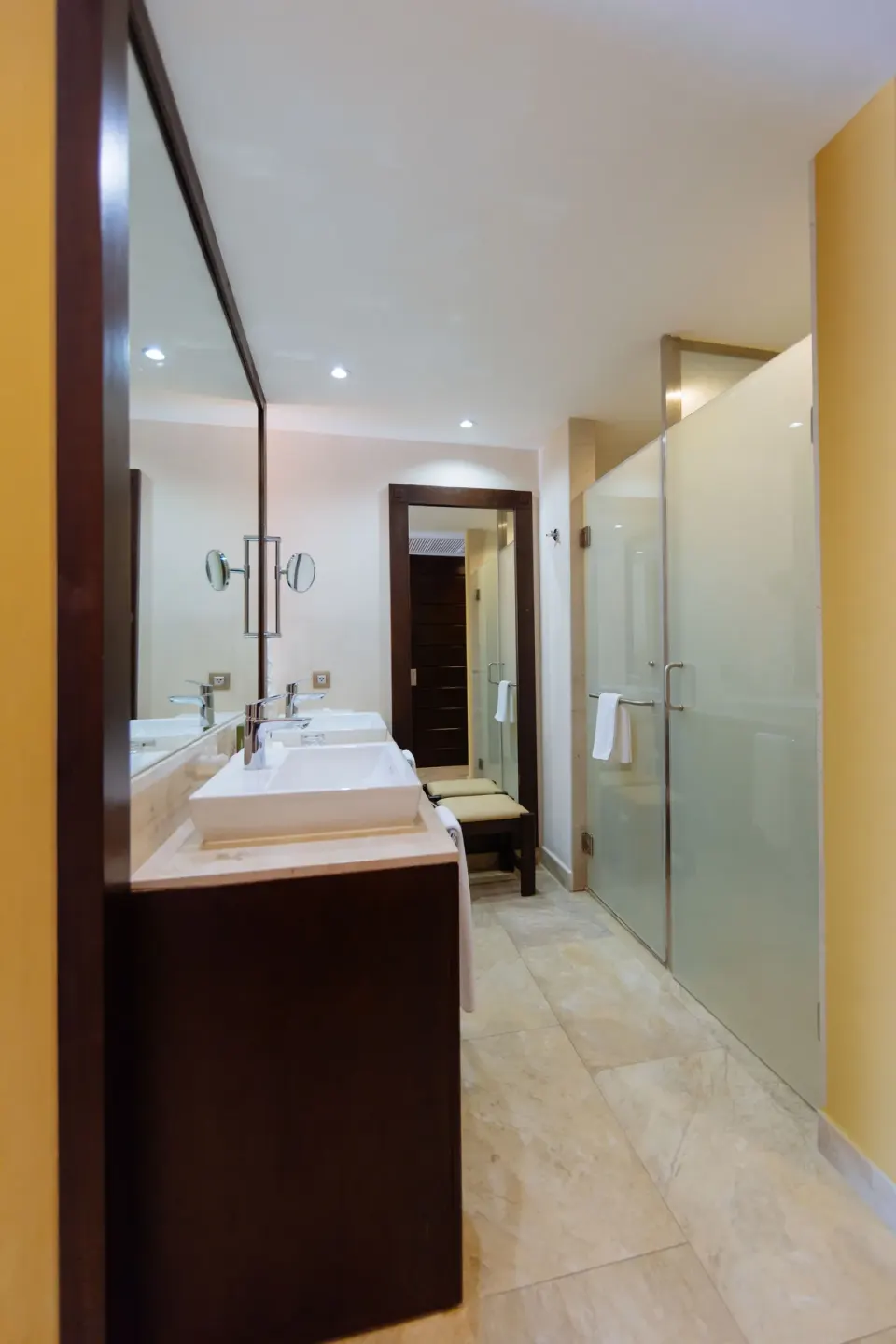Junior Suite bathroom with vanity, mirror, and frosted glass shower at Barceló Maya Caribe.