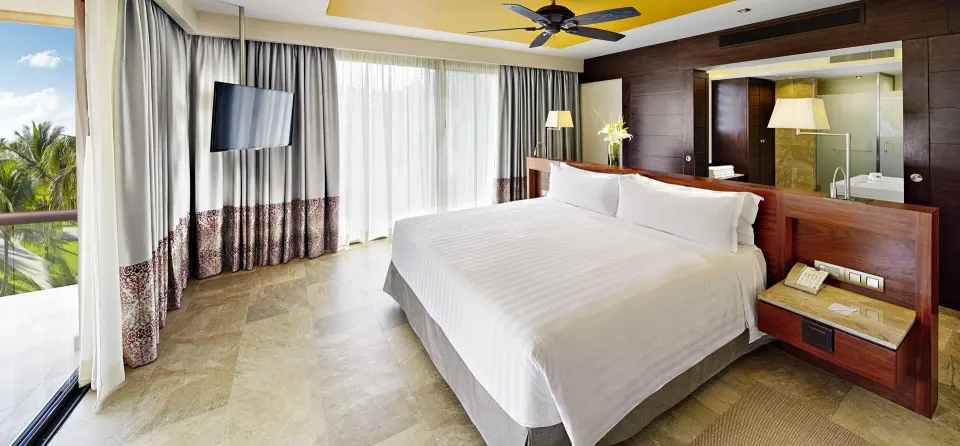 Ocean Front Premium Level suite king bed beside balcony doors at Barceló Maya Caribe.