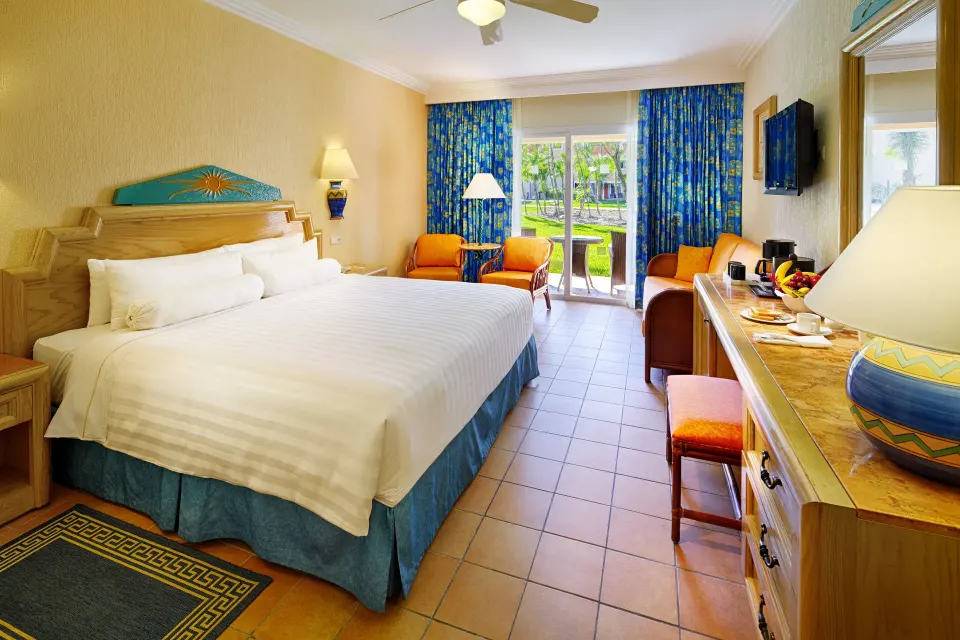Superior Room with king bed, blue curtains, and garden doors at Barceló Maya Caribe.