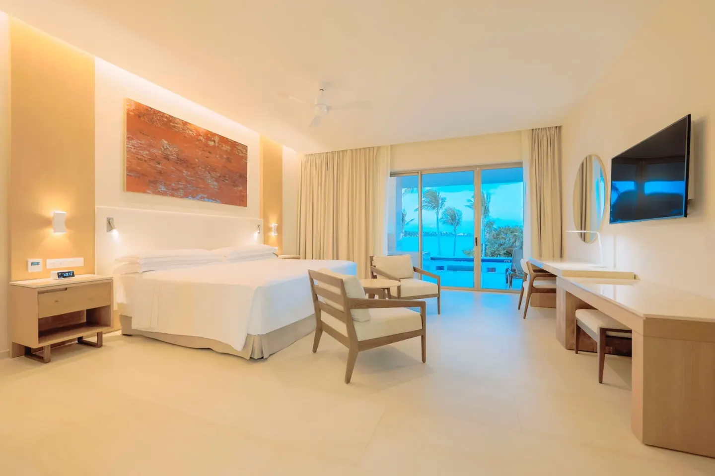 King bed guest room with seating, desk, and balcony doors at Barceló Maya Riviera.