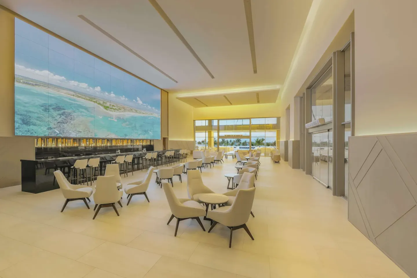 A bright lobby lounge with a long bar and ocean mural at Barceló Maya Riviera.