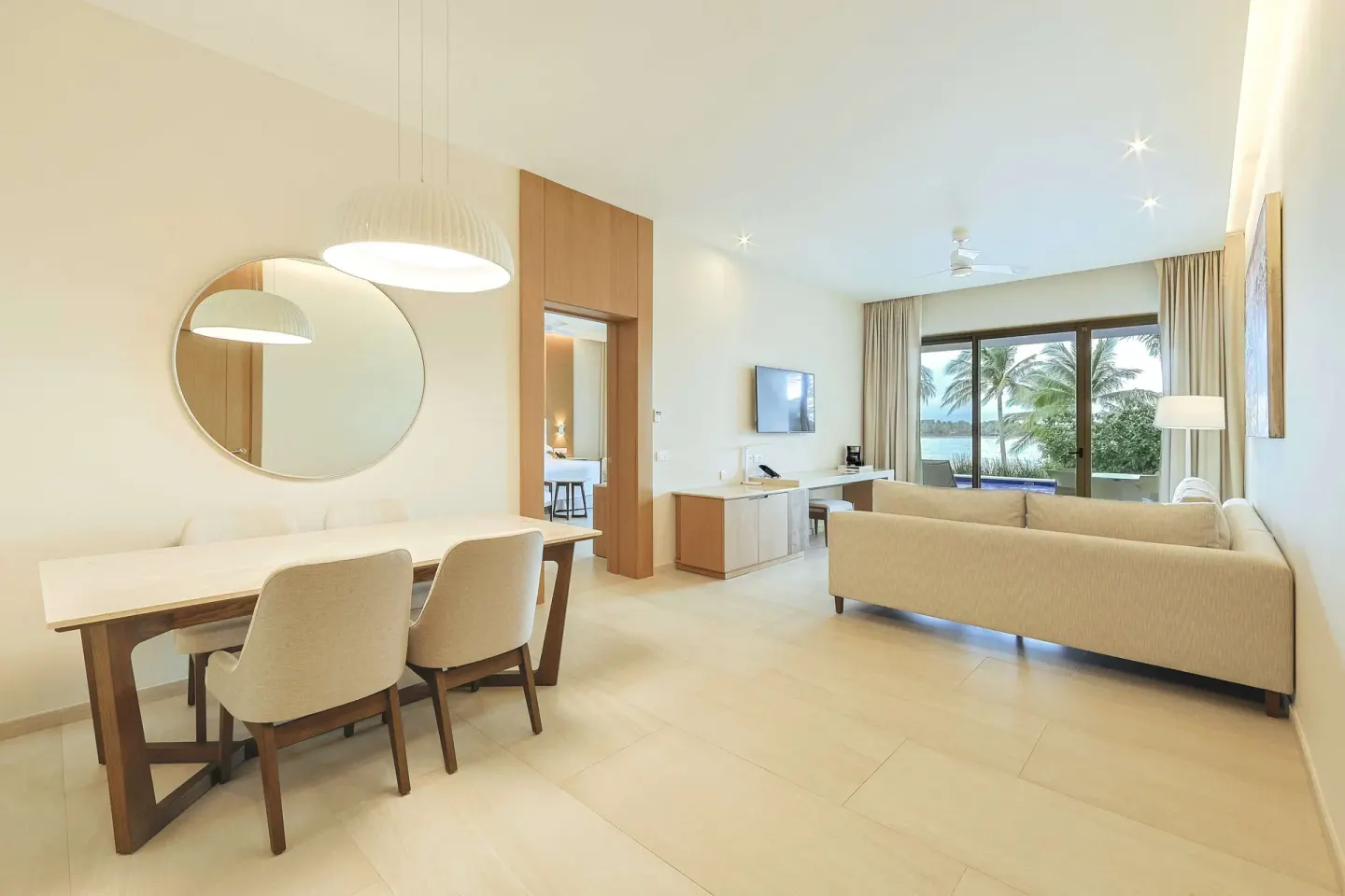 Suite living area with dining table, sofa, and palm-framed terrace at Barceló Maya Riviera.