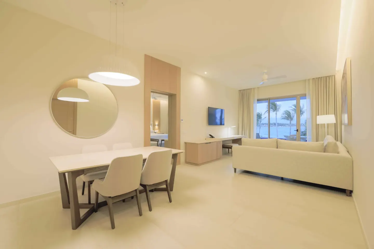 Suite living room with dining table, sofa, and ocean-facing glass doors at Barceló Maya Riviera.