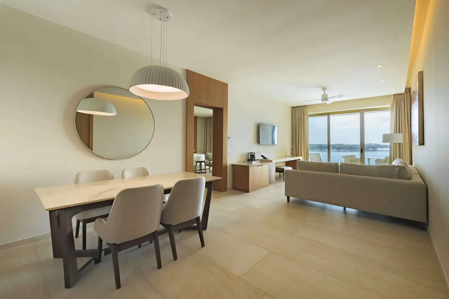 Suite living room with dining table, sofa, and water view at Barceló Maya Riviera.