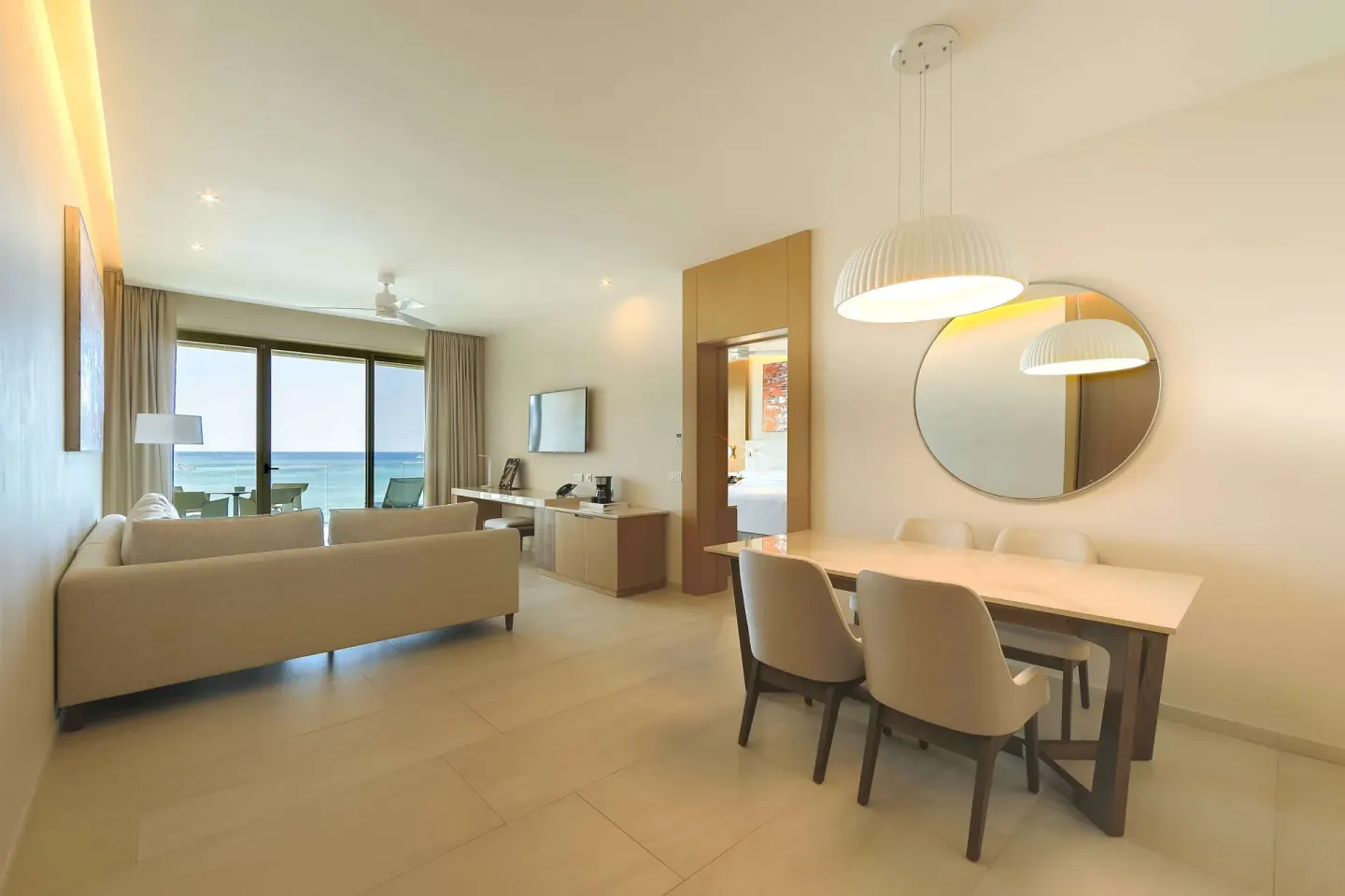 Suite lounge with dining table, sofa, and ocean-view balcony at Barceló Maya Riviera.