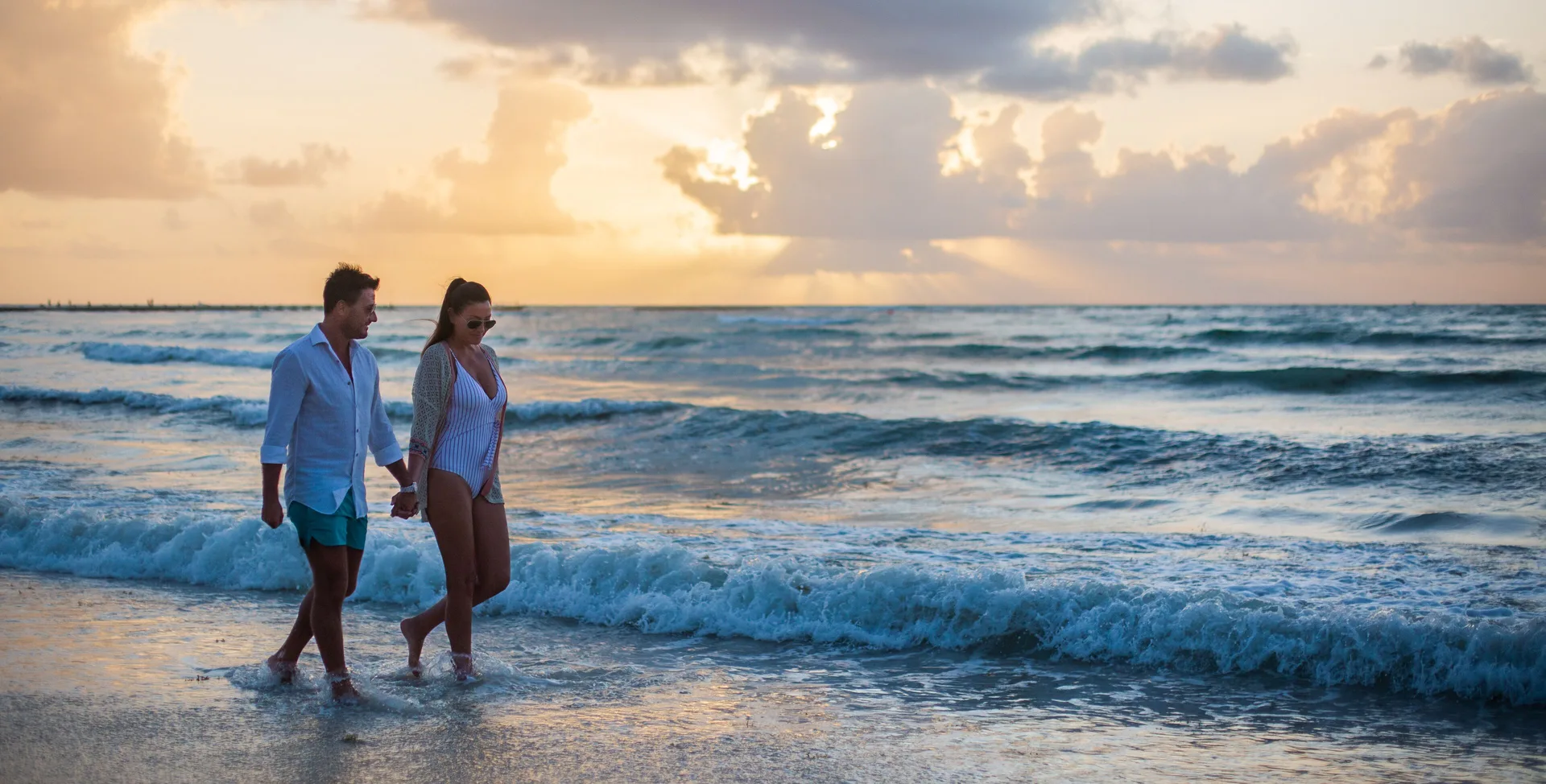 Couple walking at the surf during sunset at Barceló Maya Riviera.
