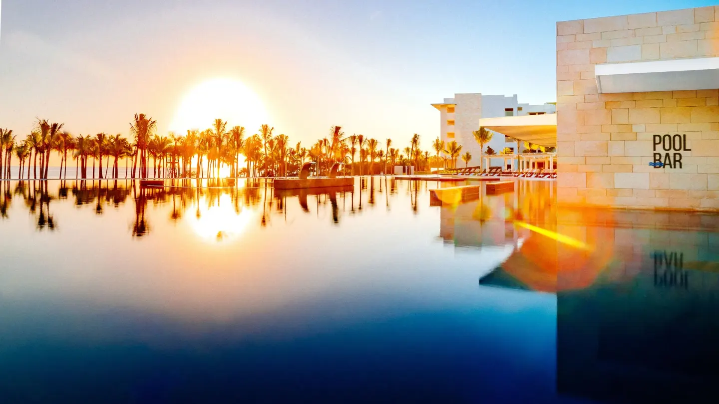 Sunset reflects across the pool beside the pool bar at Barceló Maya Riviera.