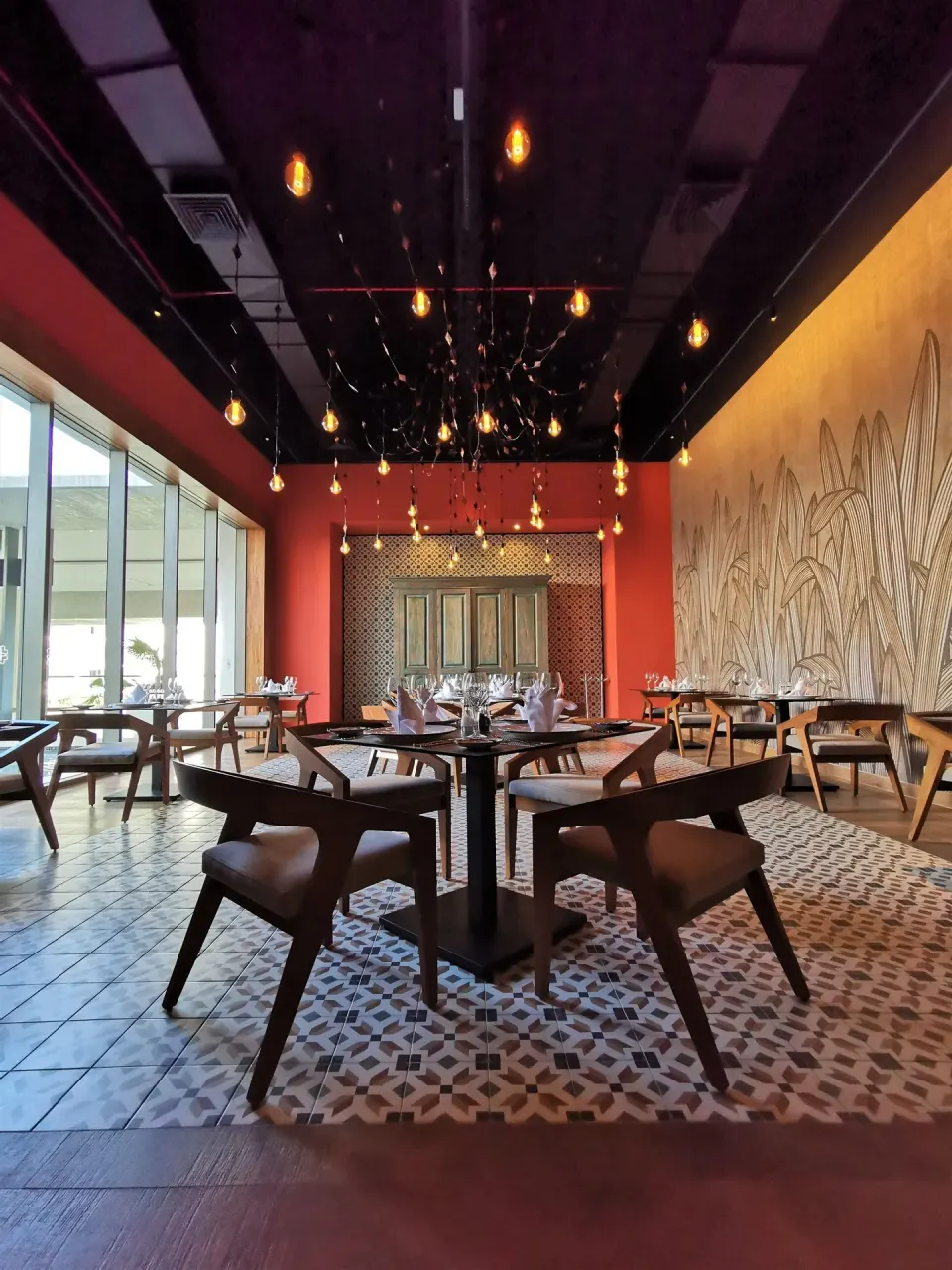 A warmly lit restaurant dining room with set tables at Barceló Maya Riviera.