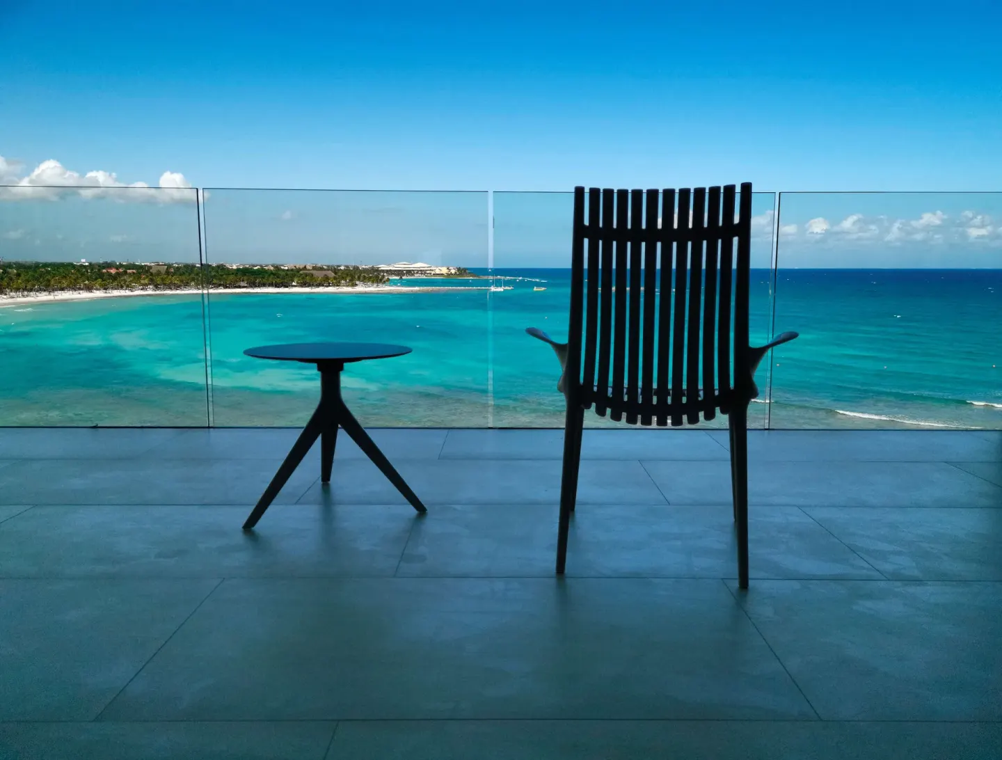 Junior Suite Oceanfront balcony with chair, table, and turquoise sea at Barceló Maya Riviera.