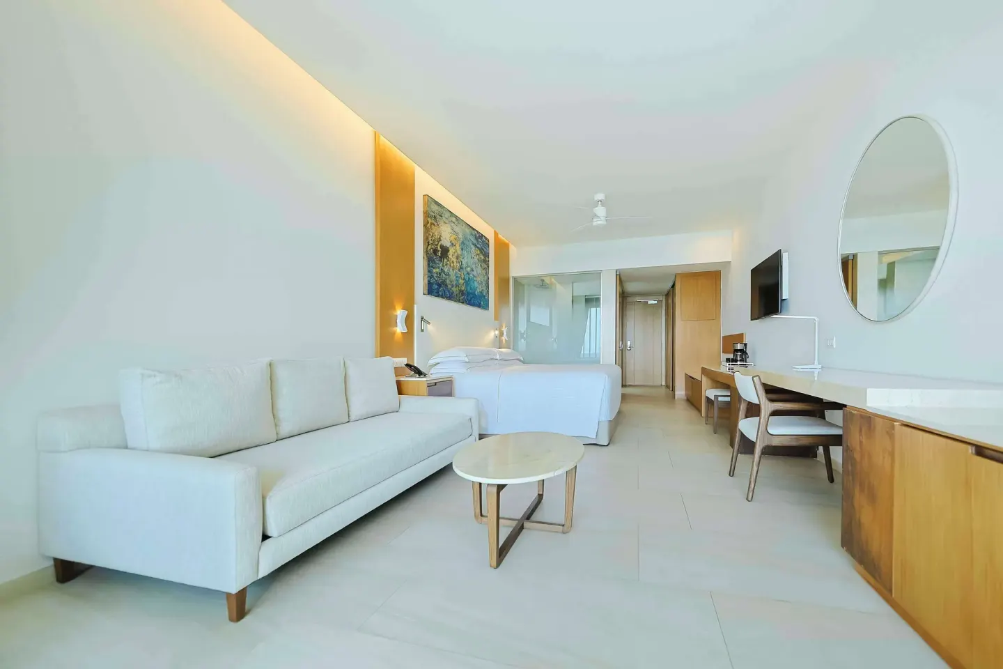 Junior Suite Oceanfront with sofa, king bed, desk, and round mirror at Barceló Maya Riviera.