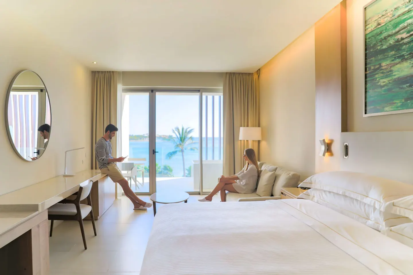 Junior Suite Oceanfront king bed, sofa, desk, and balcony view at Barceló Maya Riviera.
