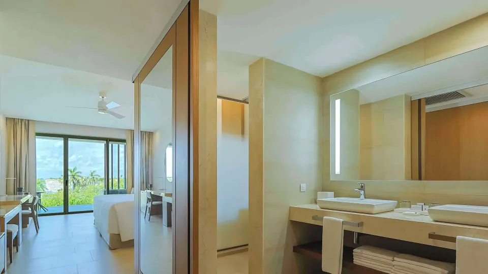 Junior Suite double vanity with towels and bedroom beyond at Barceló Maya Riviera.