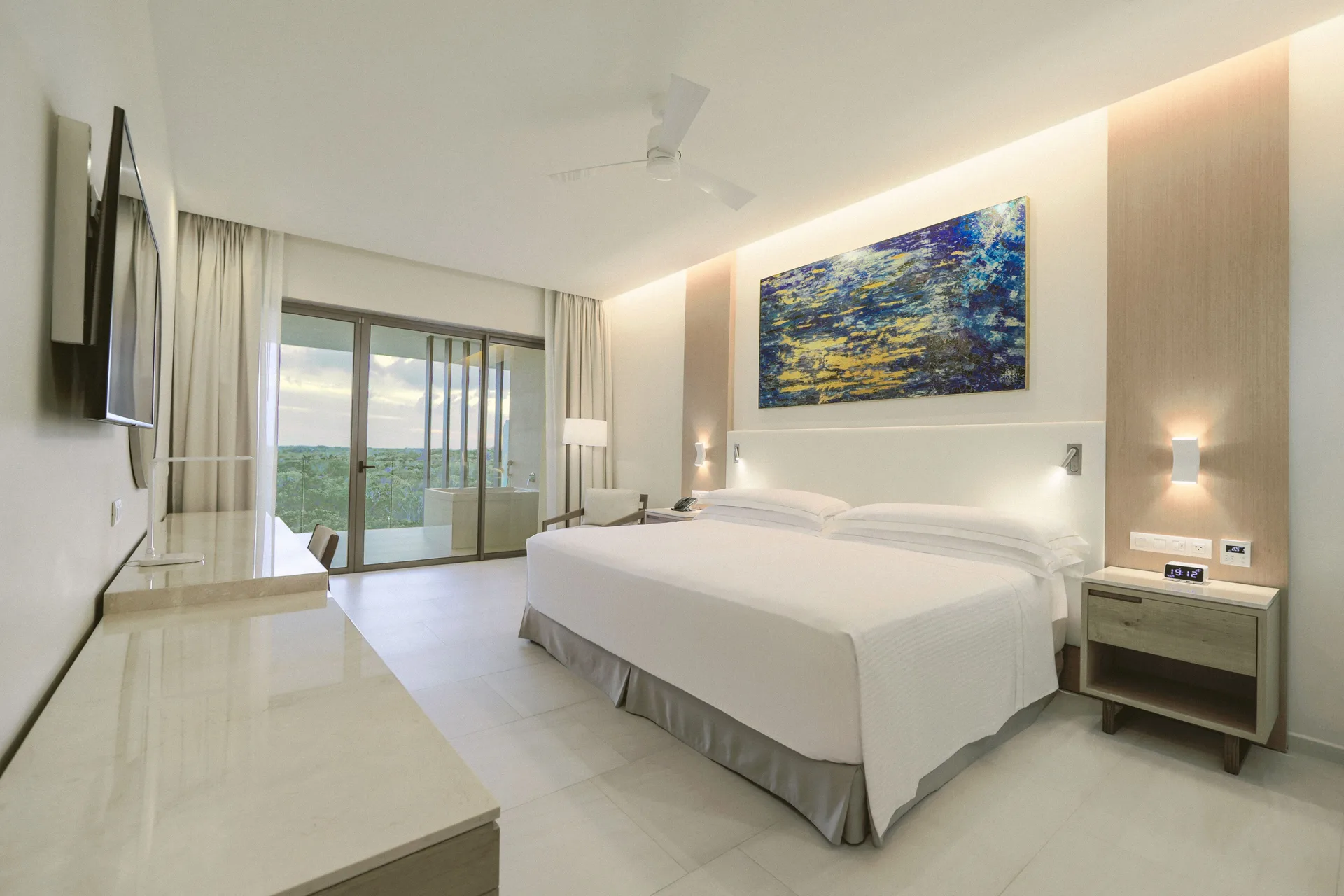 Junior Suite with king bed, balcony doors and wall-mounted TV at Barceló Maya Riviera.