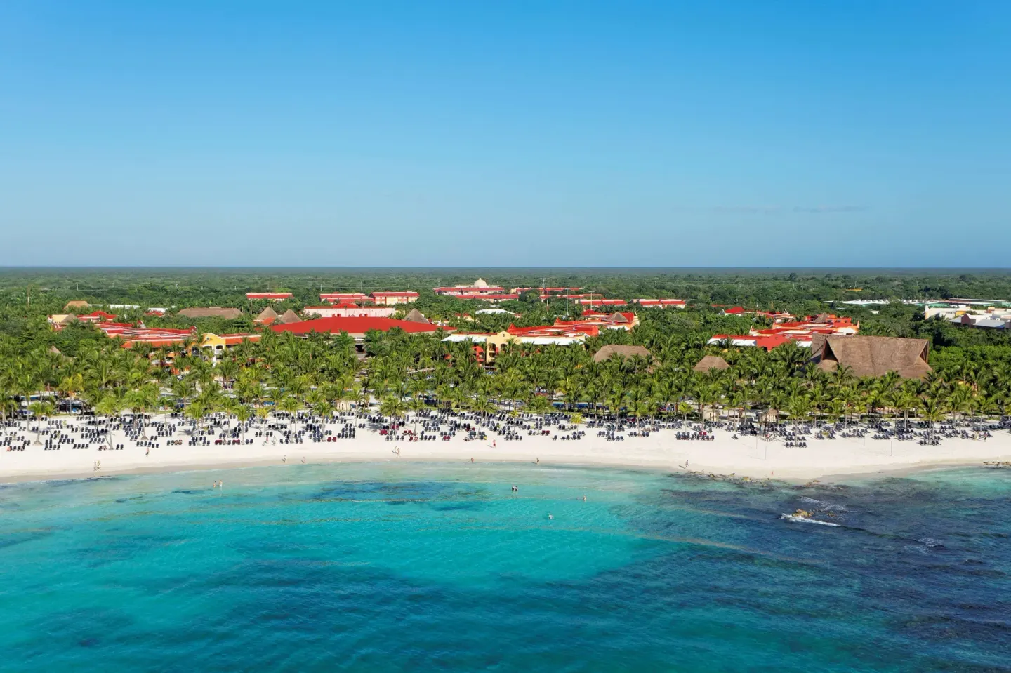 Aerial view of turquoise water, beach, and resort buildings at Barceló Maya Tropical.