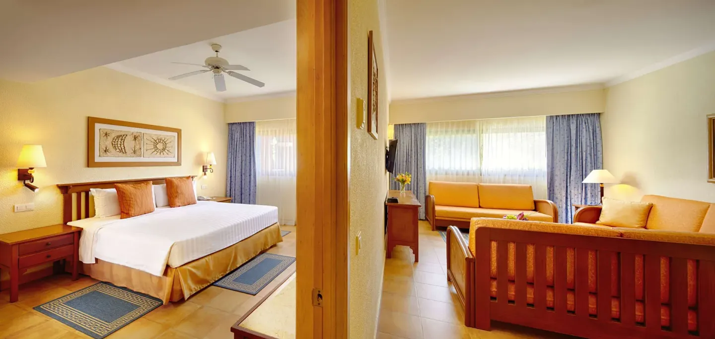 Suite bedroom with king bed and separate sitting area at Barceló Maya Tropical.