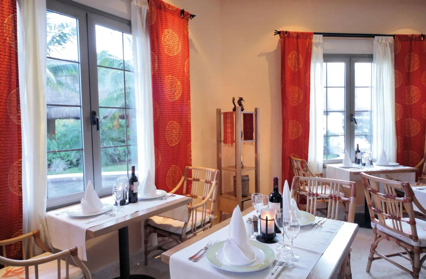 A restaurant dining room with set tables and red curtains at Barceló Maya Tropical.