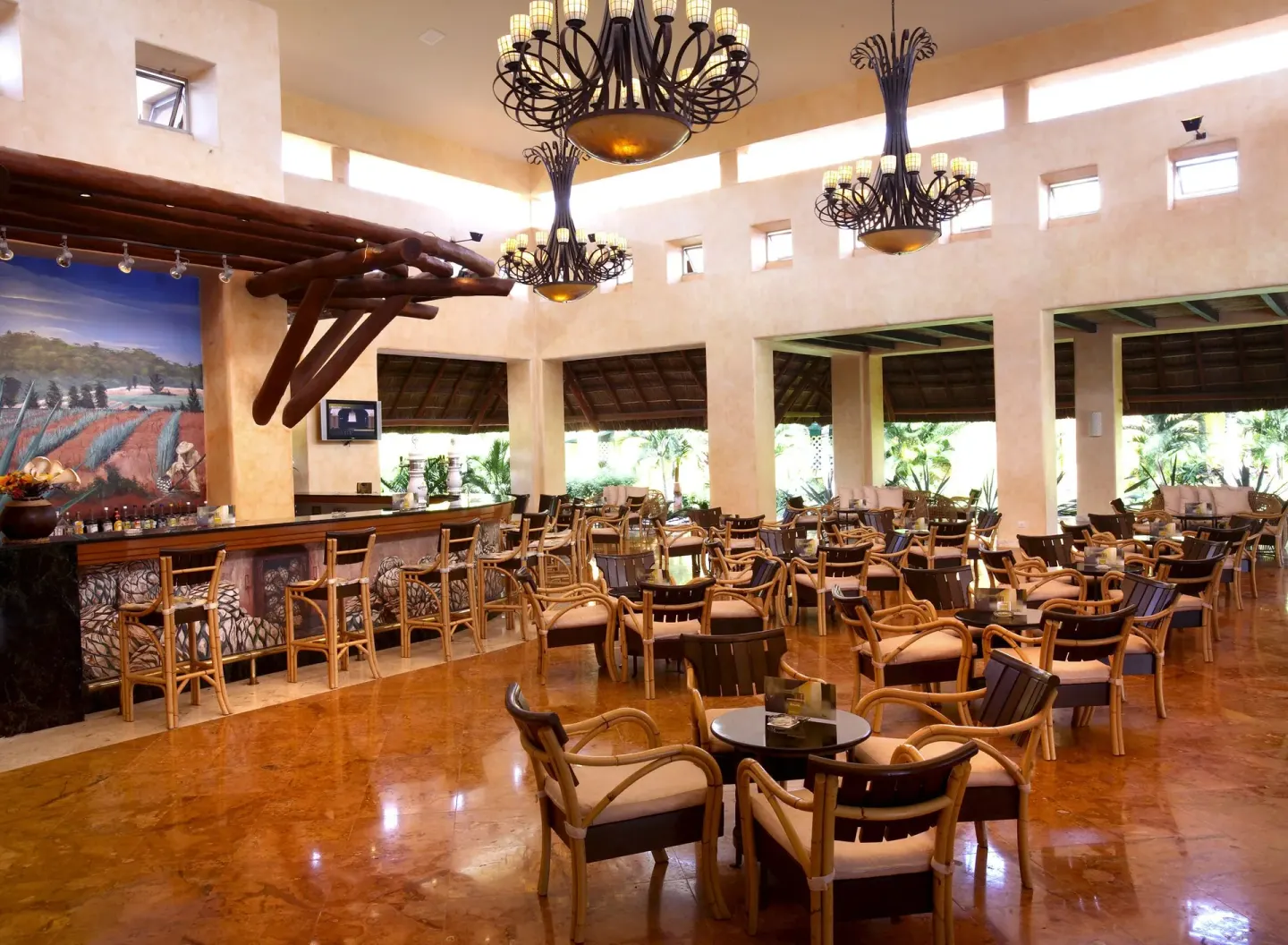 Spacious lobby bar with chandeliers and many lounge chairs at Barceló Maya Tropical.