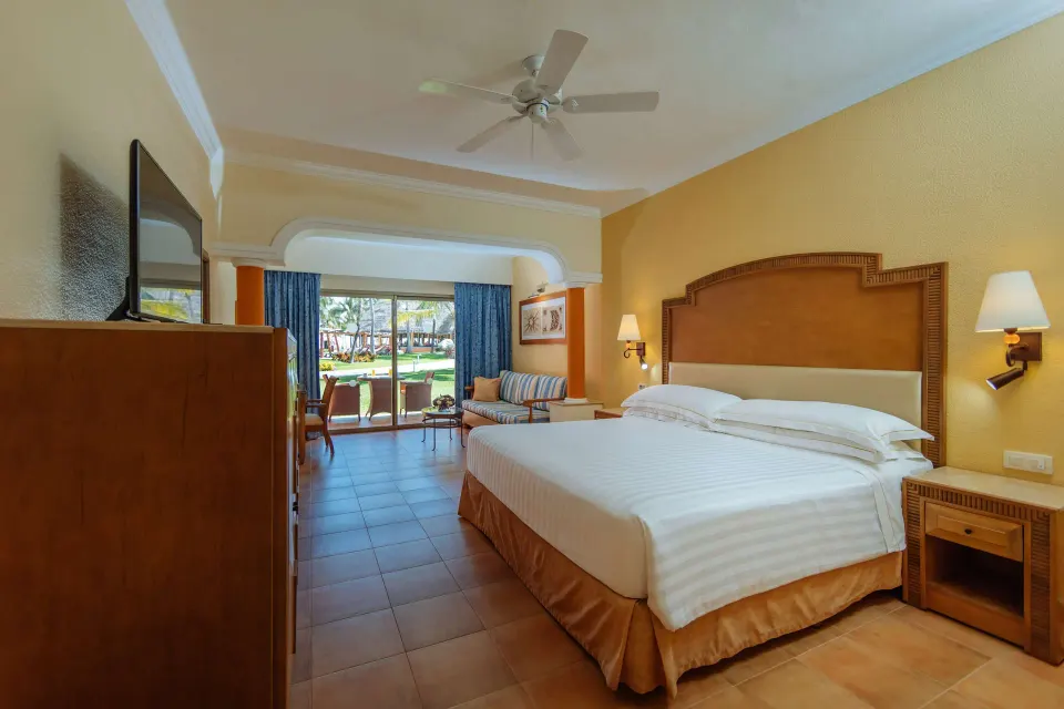 Superior Room king bed, sofa, TV, and balcony view at Barceló Maya Tropical.