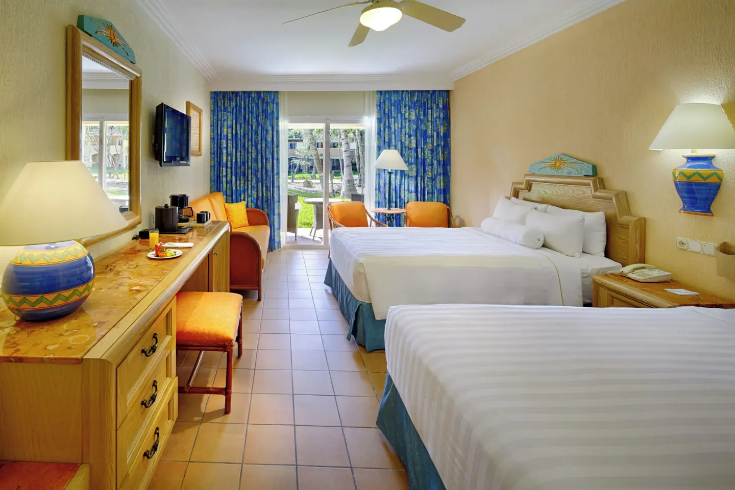 Superior Room with two beds, desk, TV, and patio doors at Barceló Maya Tropical.