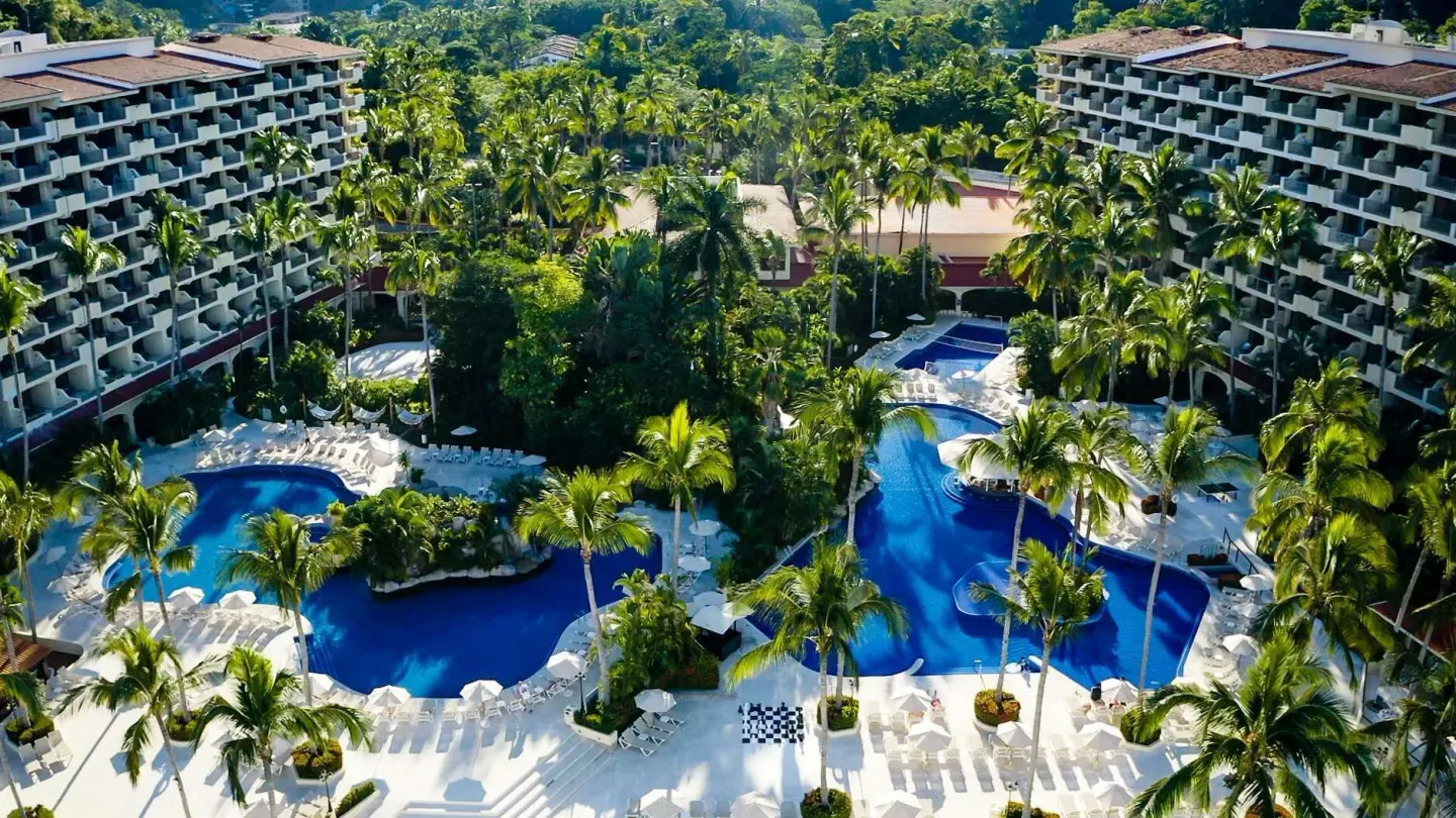 Aerial view of pools, palms, and guest room towers at Barceló Puerto Vallarta.
