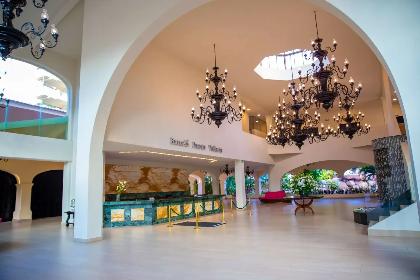 Spacious lobby at Barceló Puerto Vallarta with arches, chandeliers, and reception desk.
