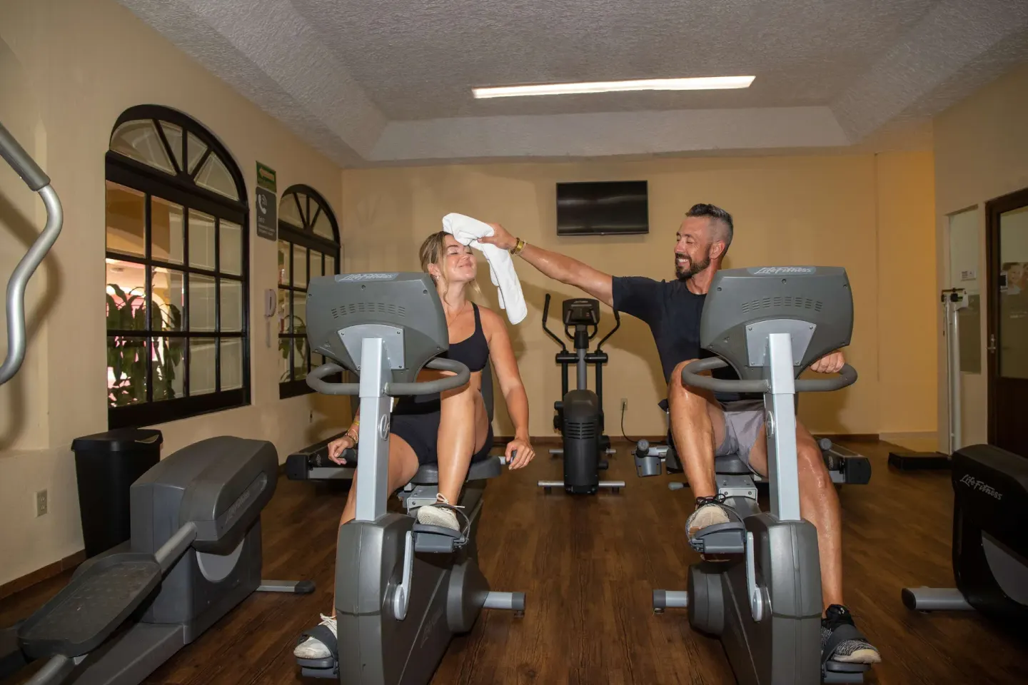 A guest hands a towel to another on exercise bikes at Barceló Puerto Vallarta.