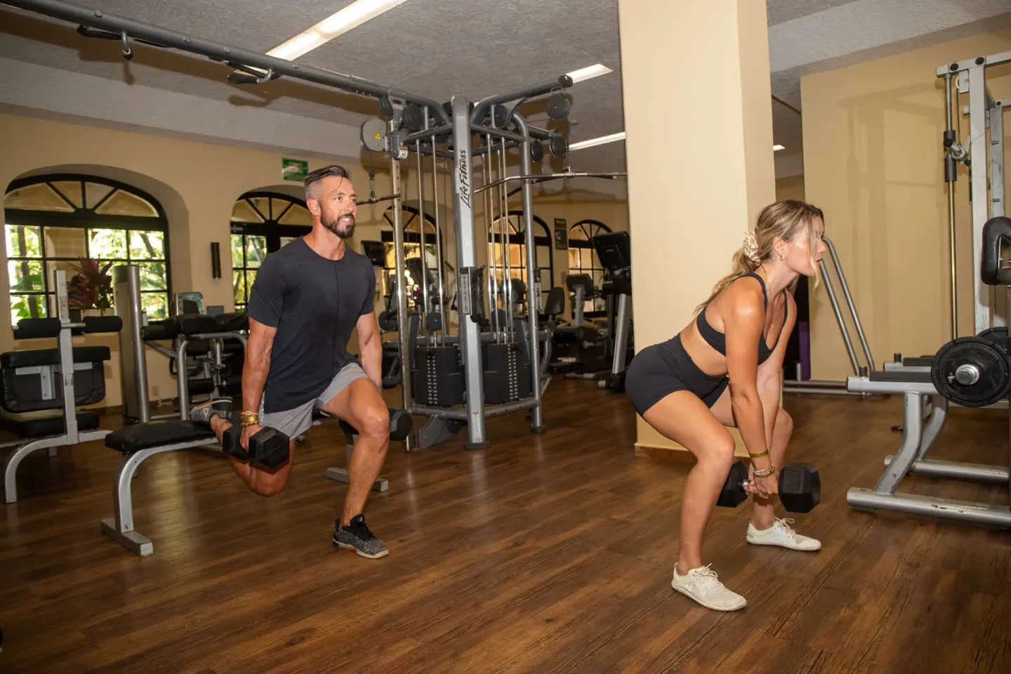 Two guests exercise with dumbbells in the gym at Barceló Puerto Vallarta.