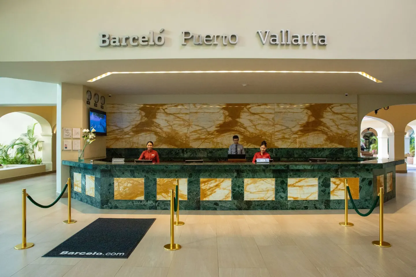 Front desk at Barceló Puerto Vallarta with staff behind a green marble reception counter.
