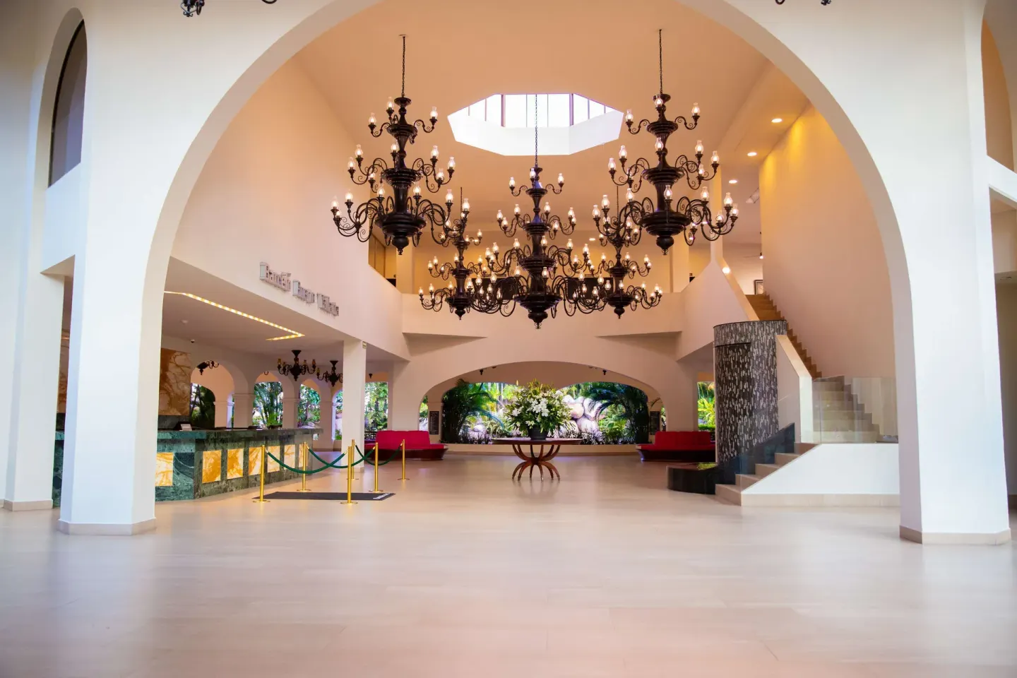Grand lobby at Barceló Puerto Vallarta with chandeliers, arches, seating, and staircase.