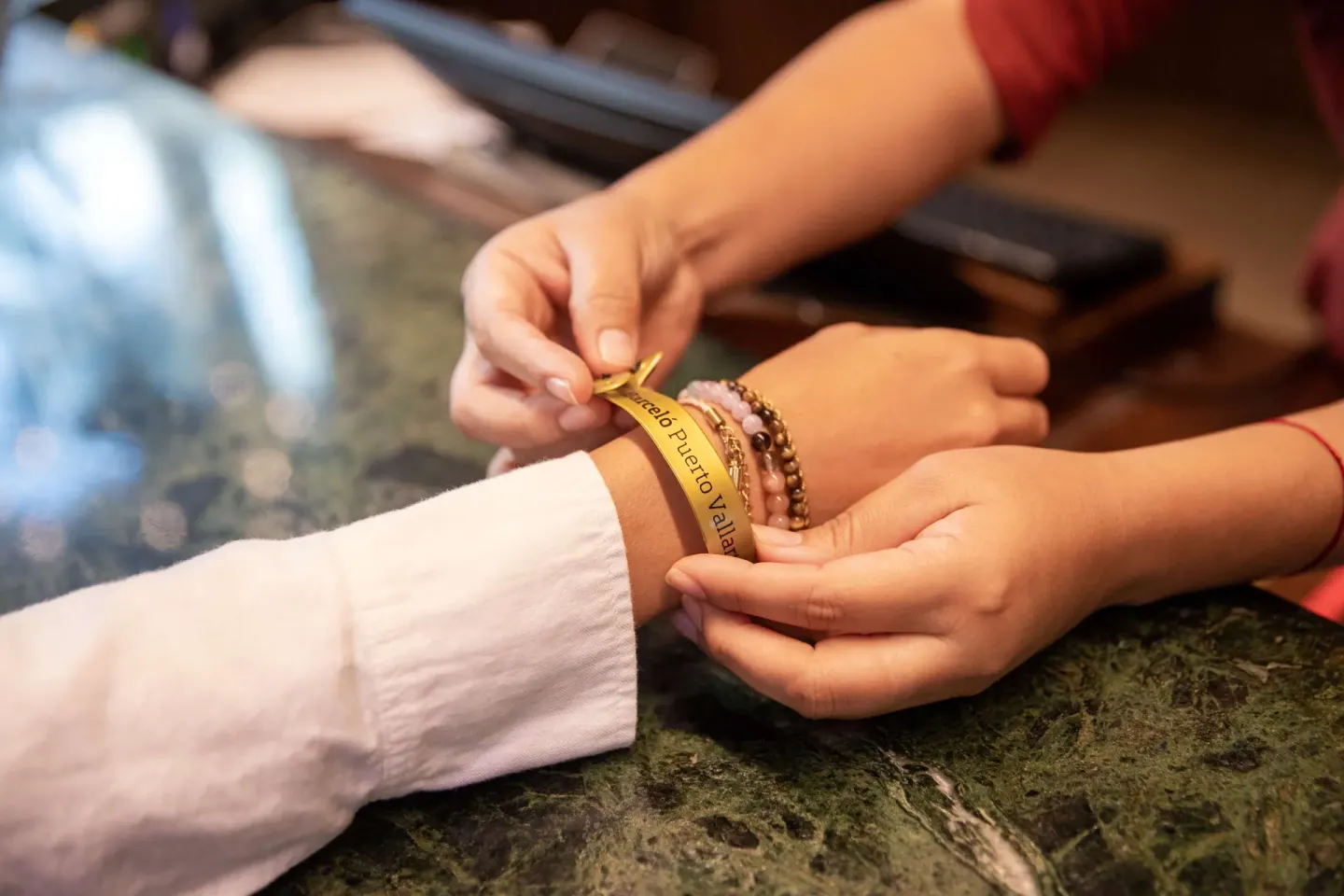 A staff member fastens a Barceló Puerto Vallarta wristband on a guest at check-in.