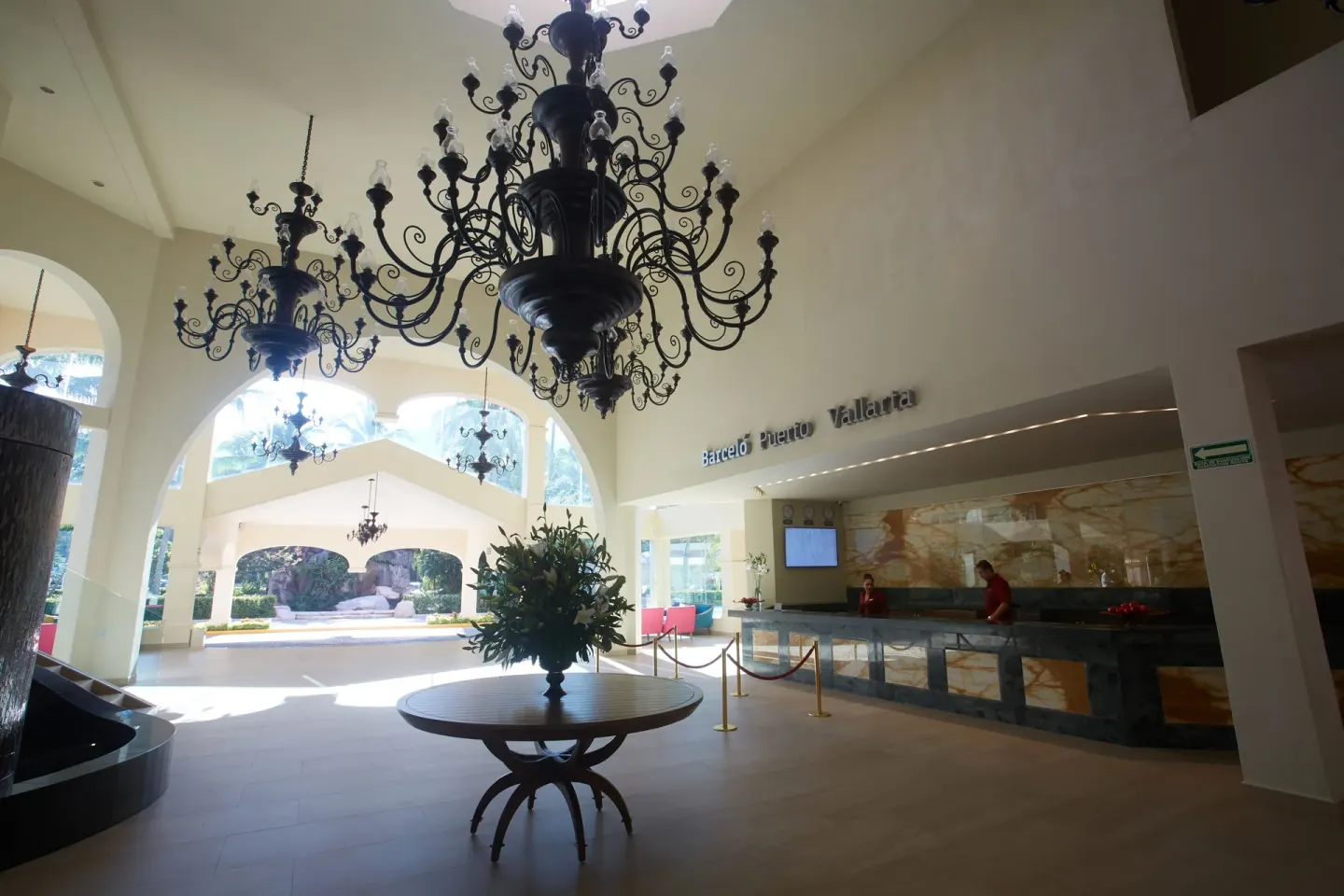 Lobby reception area at Barceló Puerto Vallarta with chandeliers, arches, and front desk.