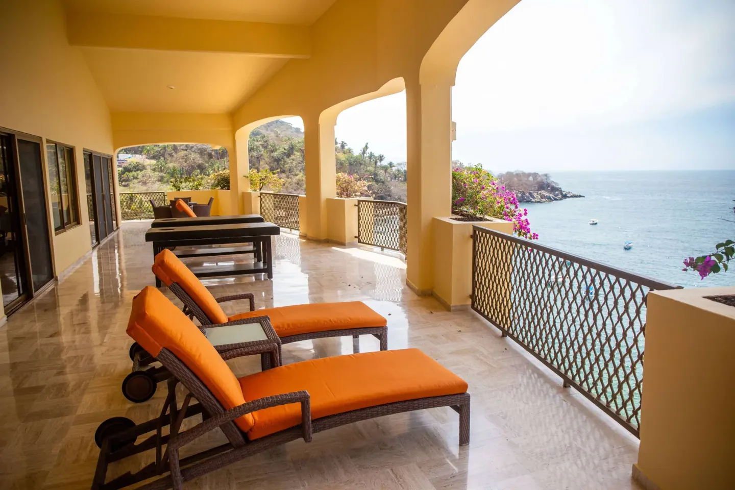 Oceanfront terrace with orange lounge chairs and arched openings at Barceló Puerto Vallarta.