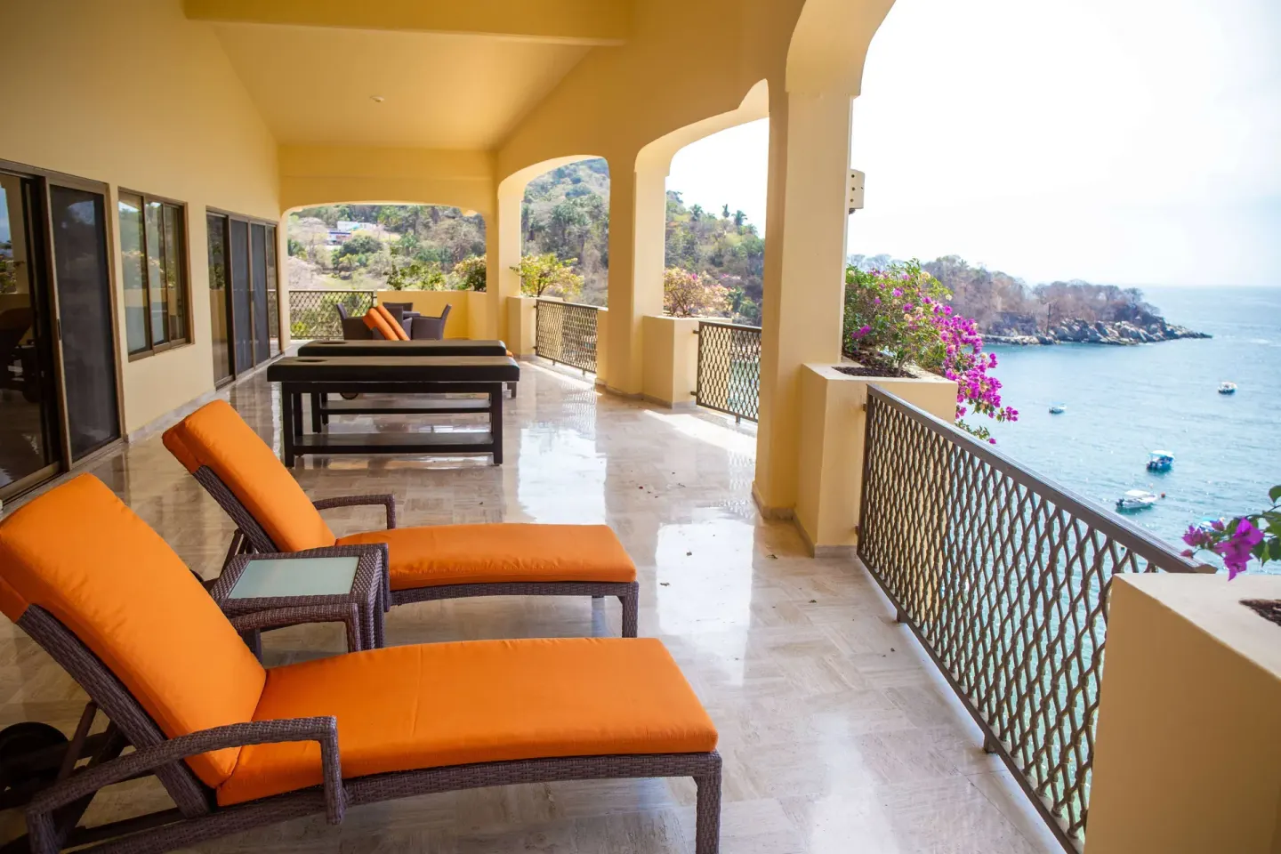 Oceanfront terrace with orange loungers and arched columns at Barceló Puerto Vallarta.