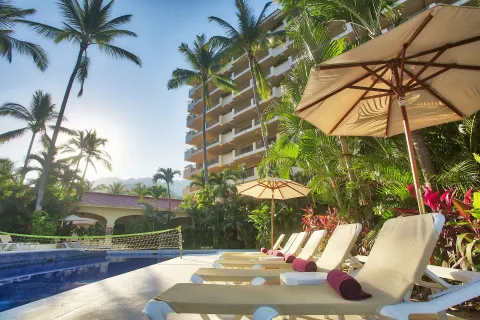 Poolside loungers under umbrellas beside palms at Barceló Puerto Vallarta.