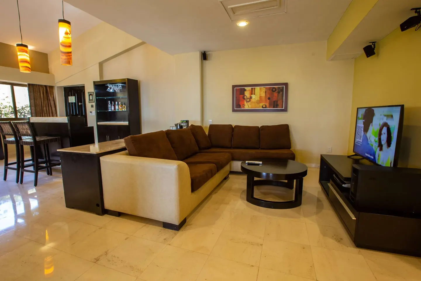 A suite sitting area with sectional sofa, bar counter, and TV at Barceló Puerto Vallarta.