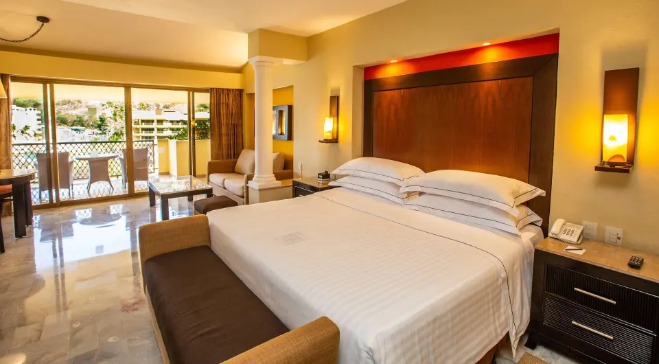 Deluxe Suite Premium Level king bed and balcony doors at Barceló Puerto Vallarta.