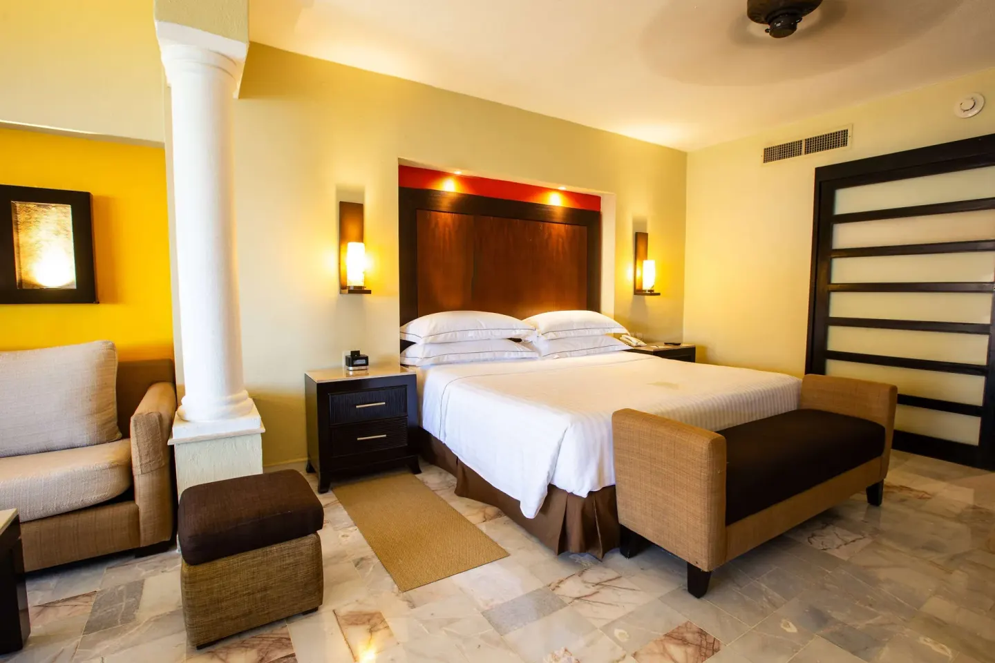 Deluxe Suite Premium Level bedroom with king bed and sofa at Barceló Puerto Vallarta.