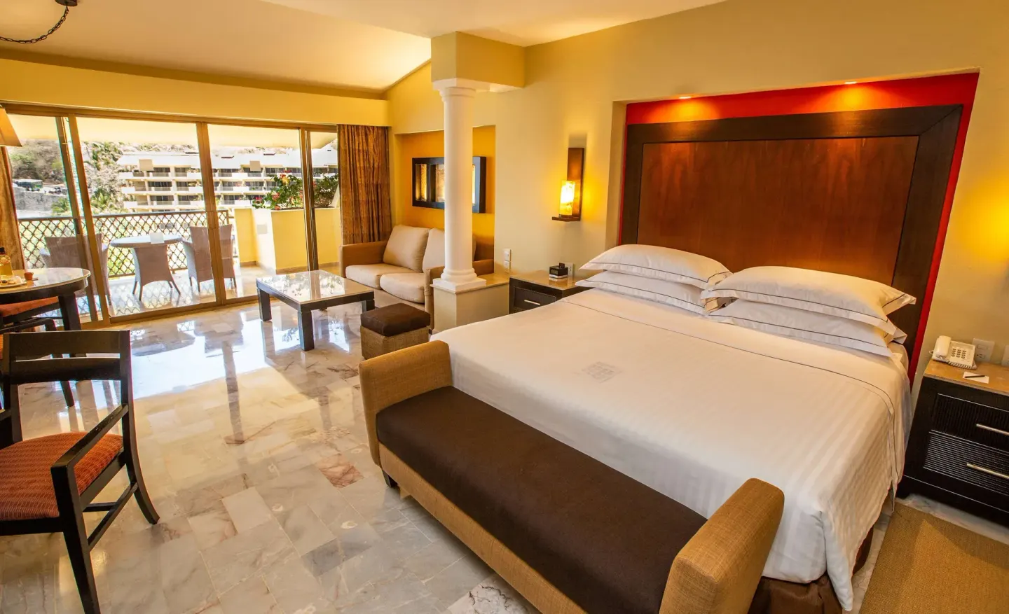 Deluxe Suite king bed with sofa, coffee table and balcony at Barceló Puerto Vallarta.