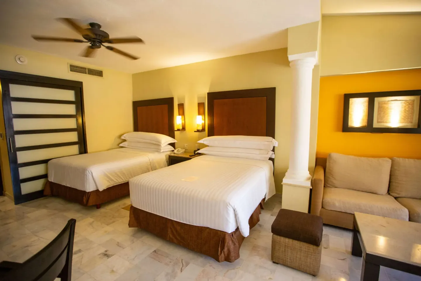 Deluxe Suite with two beds and a sofa seating area at Barceló Puerto Vallarta.
