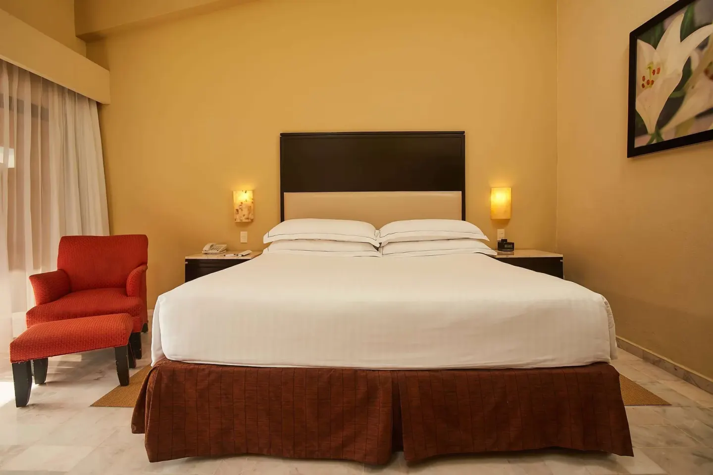Family Room king bed with red chair and floral artwork at Barceló Puerto Vallarta.